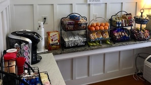 Een buffetgedeelte met snacks, waaronder chips, mandarijnen en drankjes, met een bordje dat aangeeft dat gasten gratis kunnen genieten van snacks.