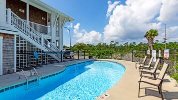 Una piscina al aire libre, sillones reclinables de piscina