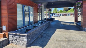 Un edificio moderno con un letrero que dice 'WELCOME', escalones de piedra y un estacionamiento.