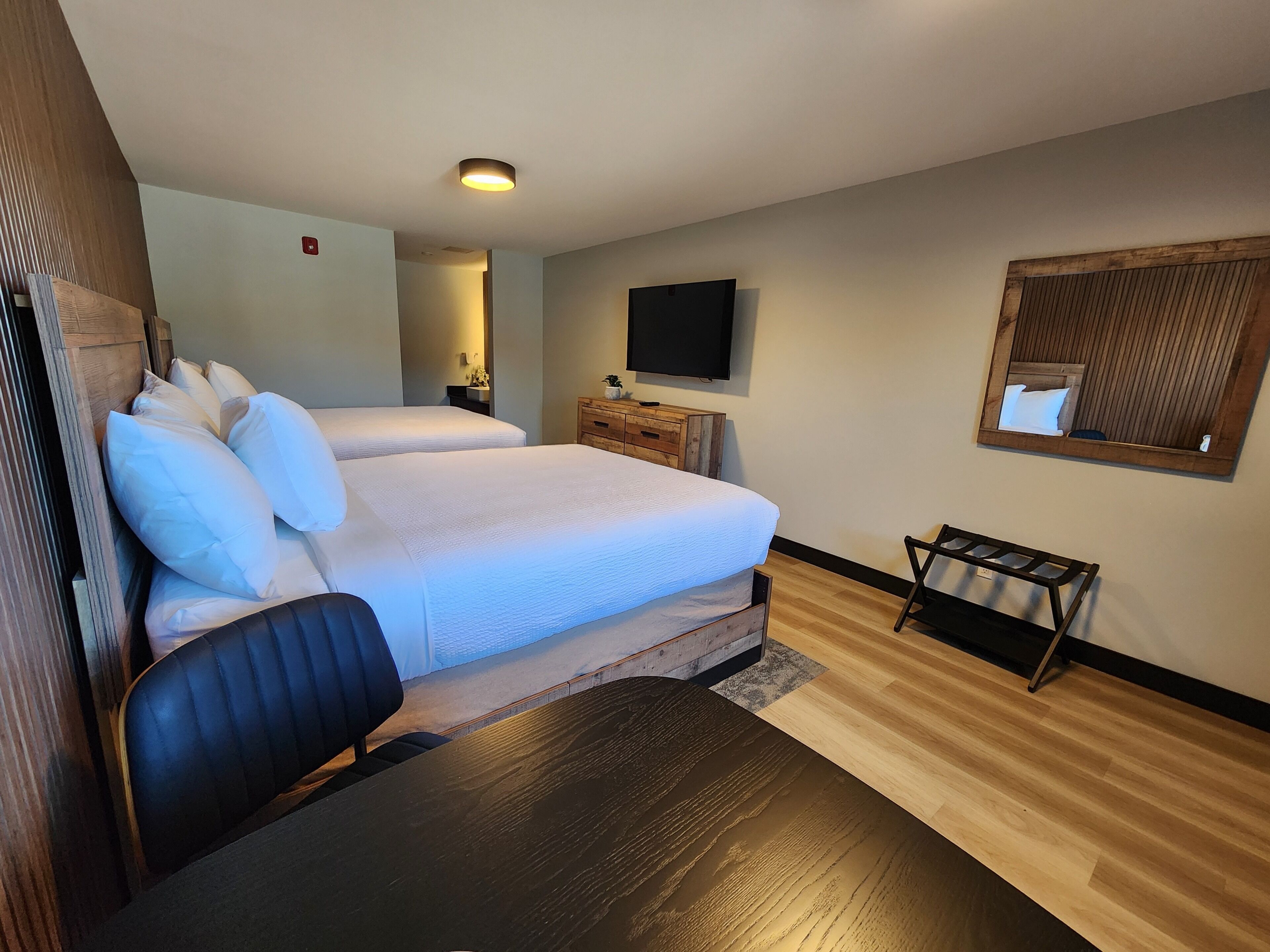 Una habitación de hotel con una cama, un televisor, un aparador de madera y una silla.