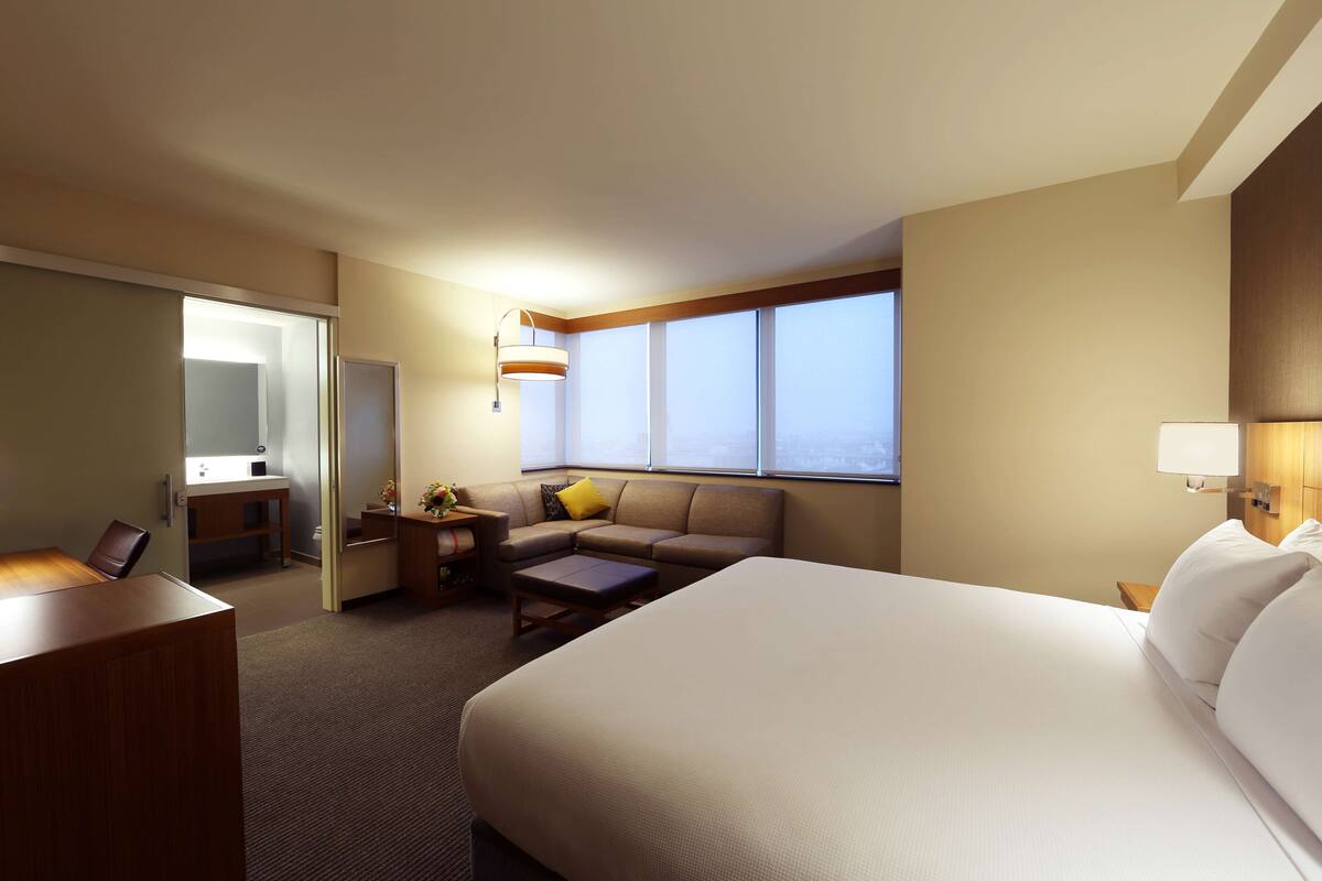 Ein Hotelzimmer mit einem großen Bett, einer Sitzecke, einem Schreibtisch und einem Fenster mit Blick.