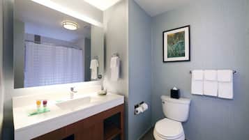 Un baño moderno con un espejo grande, un lavabo blanco, un inodoro y un cuadro en la pared.