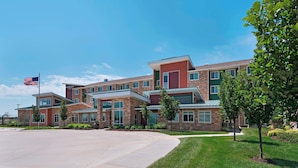 A multi-story building with a brick facade, large windows, and a flagpole with an American flag.