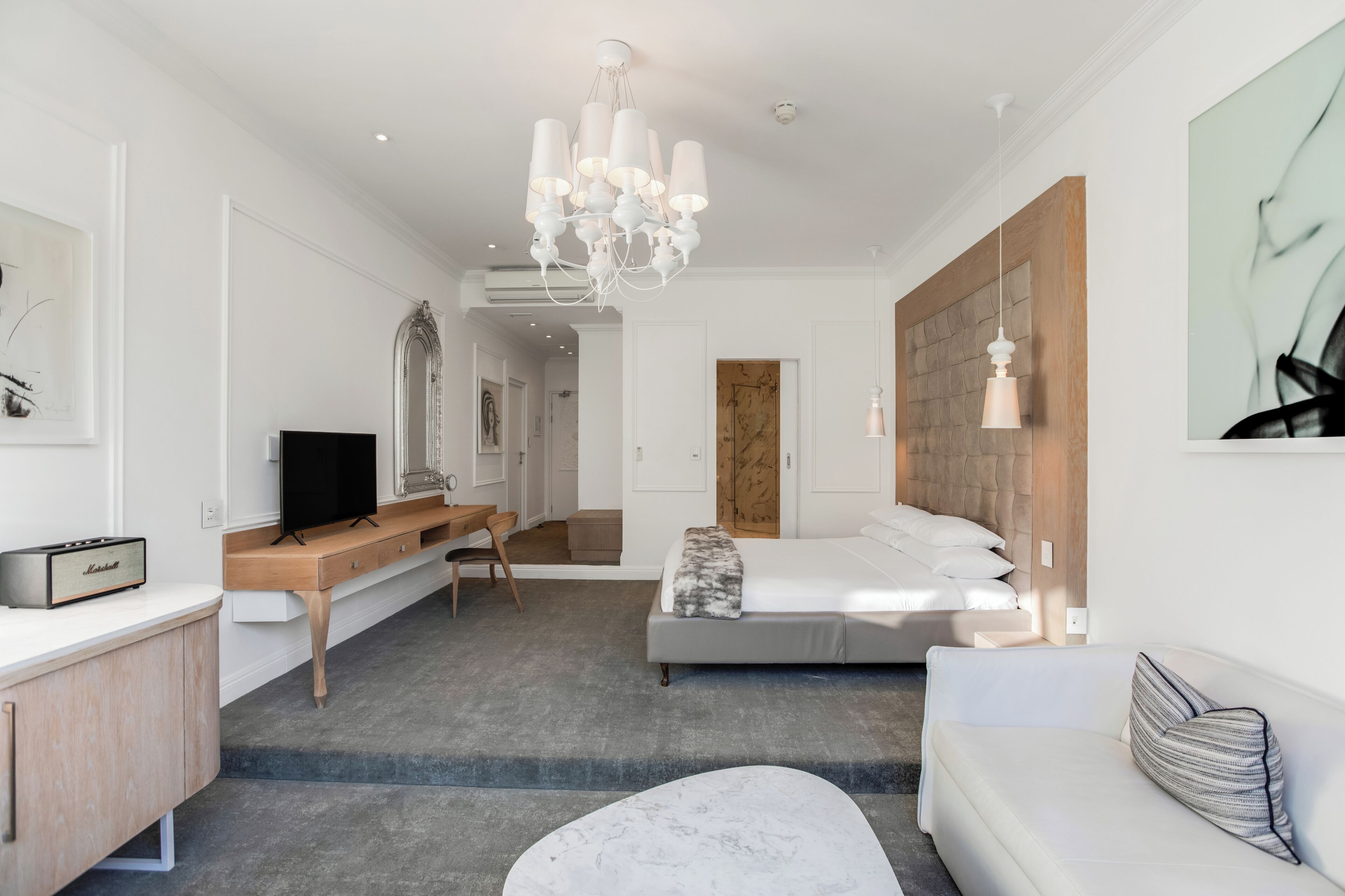 A modern hotel room with a bed, a sofa, a desk, and a television.