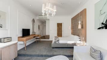 A modern hotel room with a bed, a sofa, a desk, and a television.