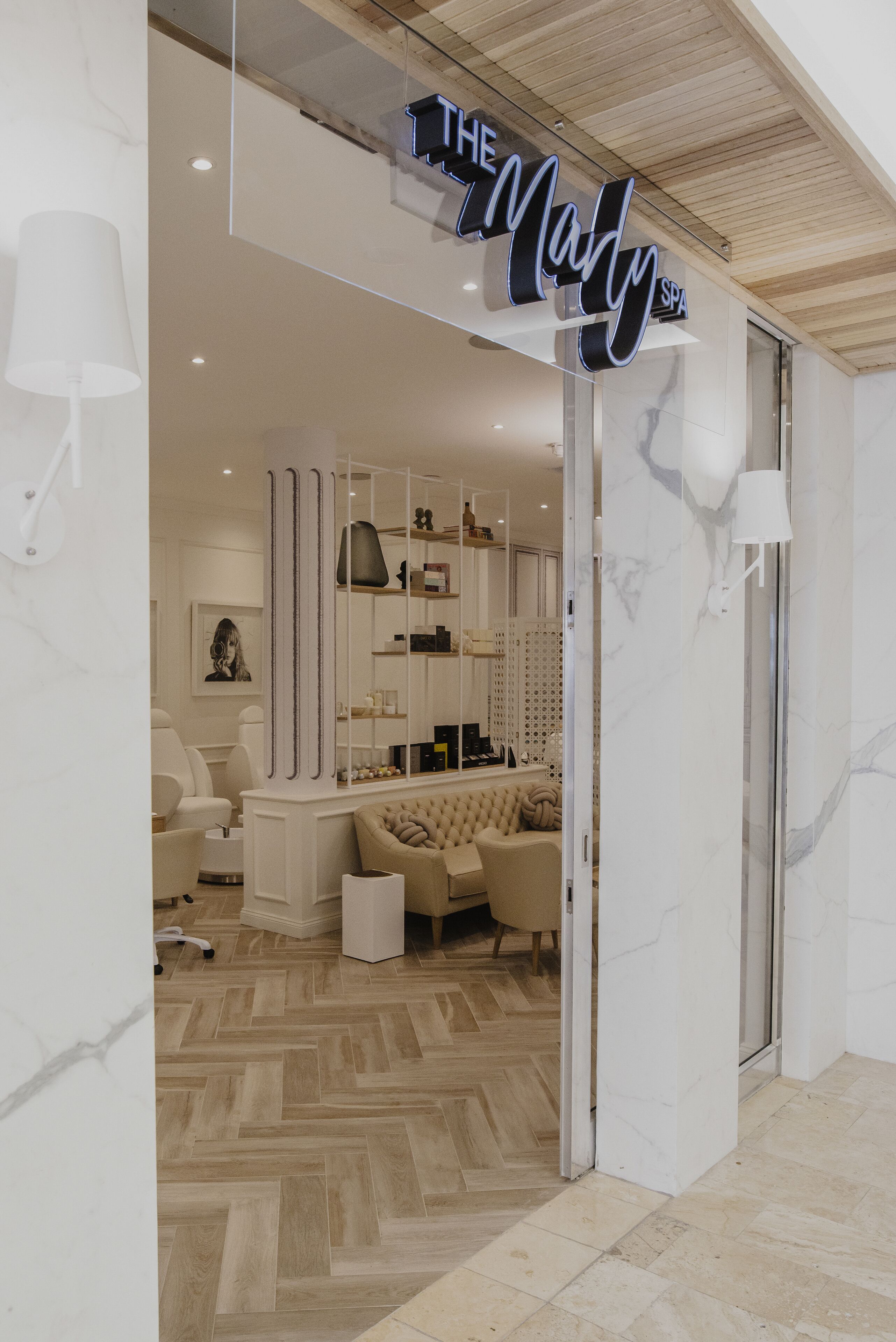 Interior moderno de um spa, com área de recepção, assentos e placa visível para 'The Mary Spa'.