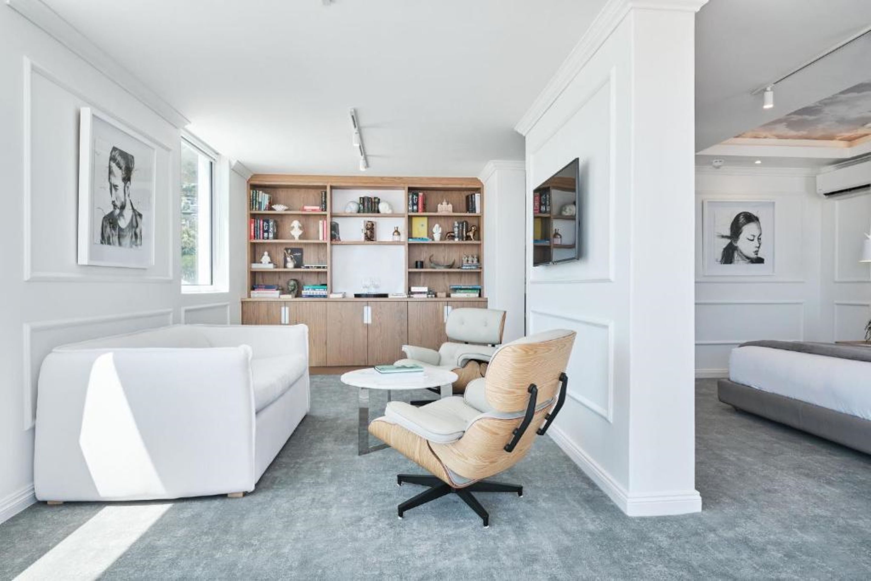 Una sala de estar moderna con un sofá blanco, una estantería de madera y una mesa de centro redonda.
