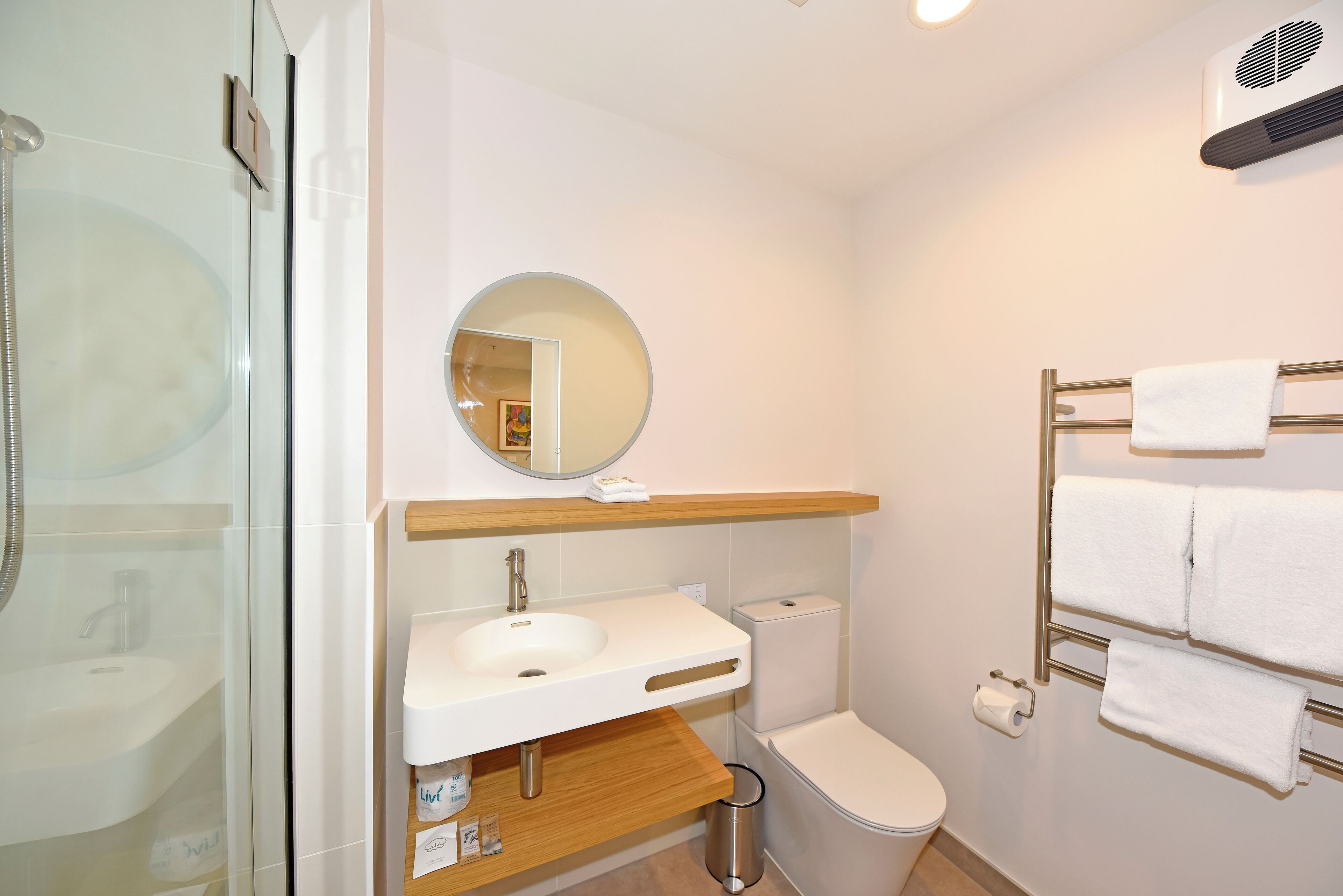 A modern bathroom with a glass shower enclosure, a white sink, a toilet, and a towel rack.