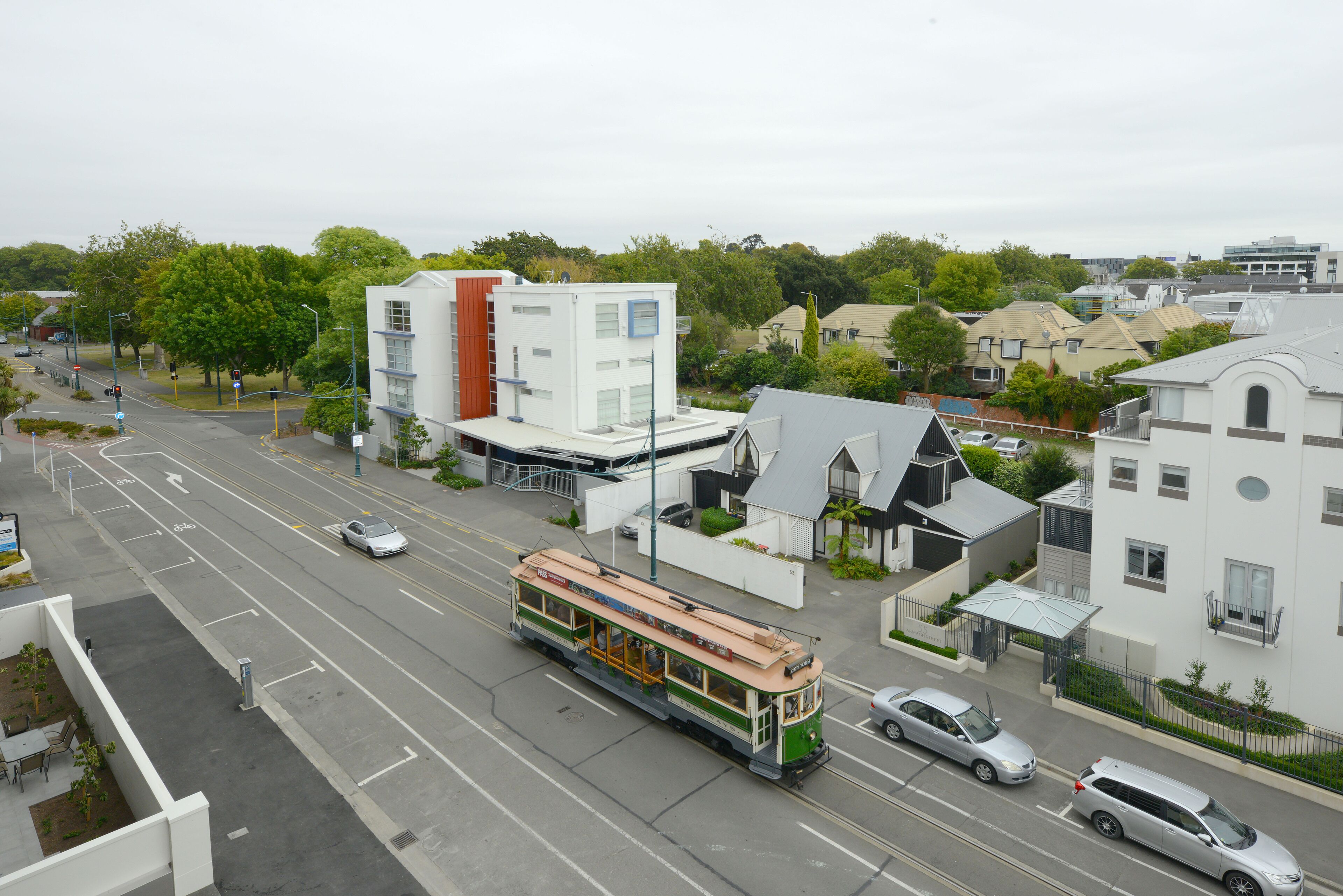 A tram on a city street with buildings and cars.