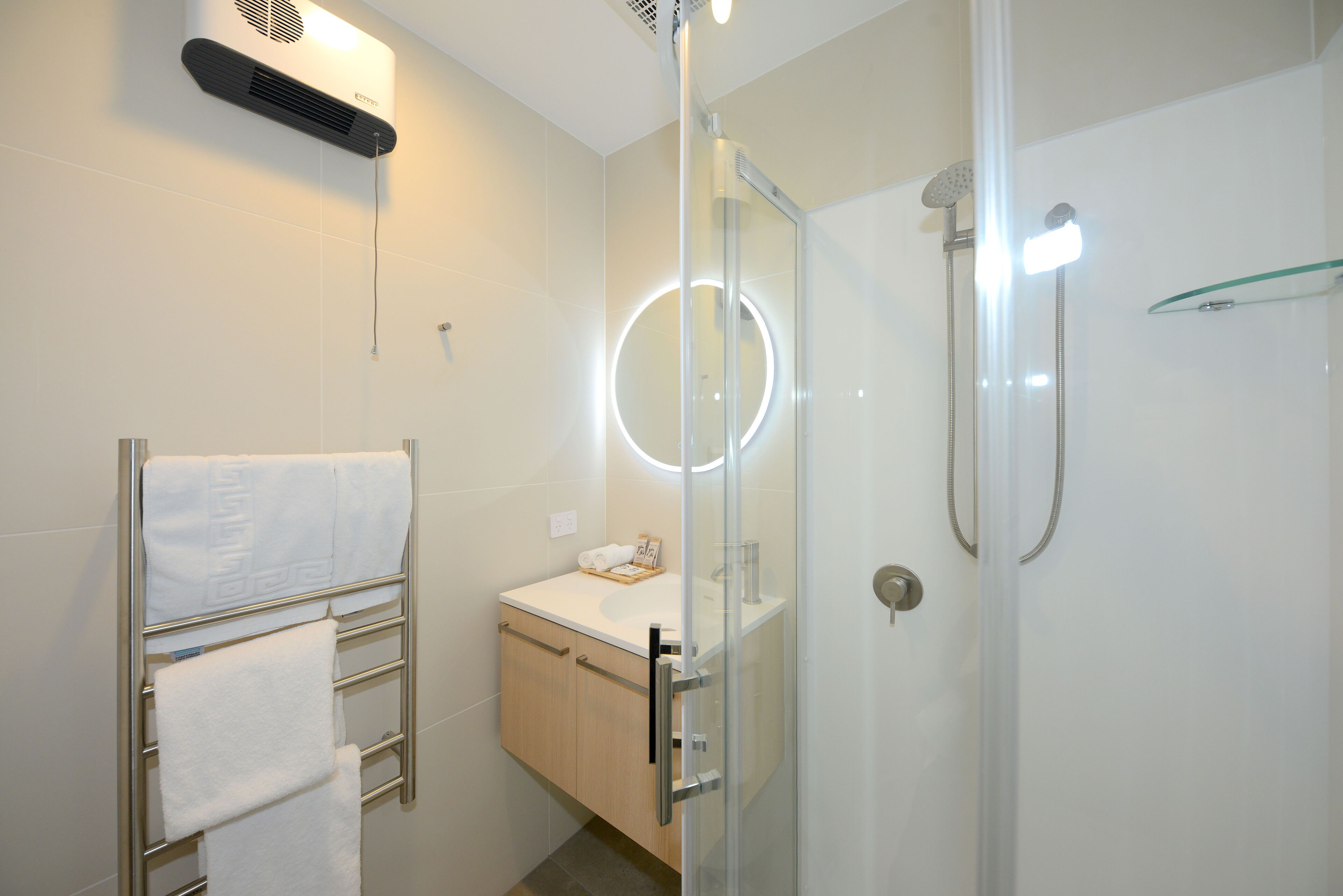 A modern bathroom with a glass-enclosed shower, a towel rack, and a vanity with a mirror.