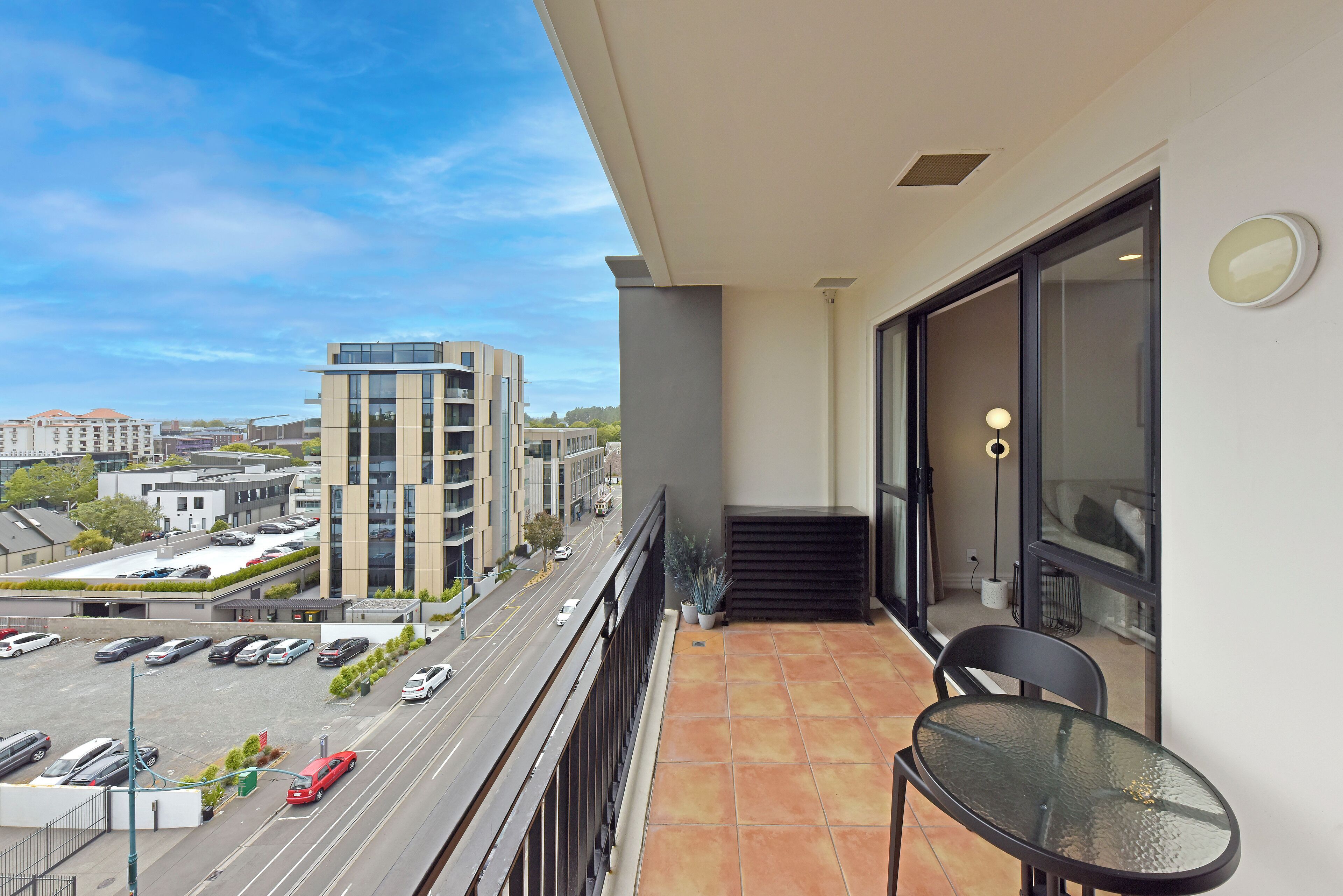A balcony with a view of a parking lot and buildings.