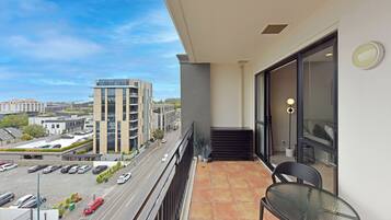 A balcony with a view of a parking lot and buildings.