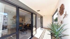 A modern interior with a glass door leading to a living area, a potted plant, and a decorative metal piece on the wall. - West Fitzroy Apartments (Christchurch)