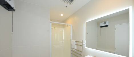 A modern bathroom with a glass-enclosed shower, a white sink with a mirror, and a toilet.
