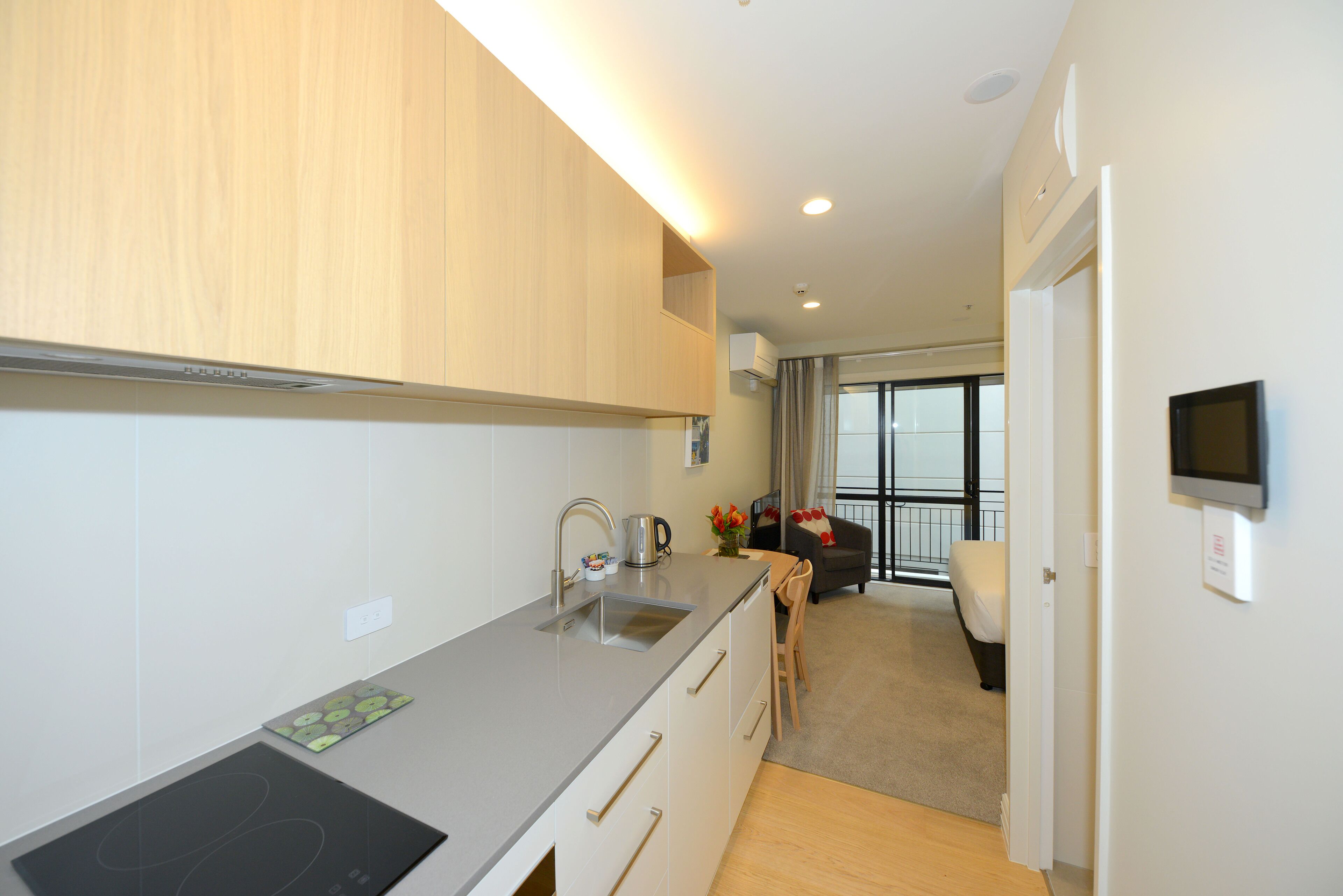 A modern kitchen with a built-in stove, a sink, and a dining area with a table and chairs.