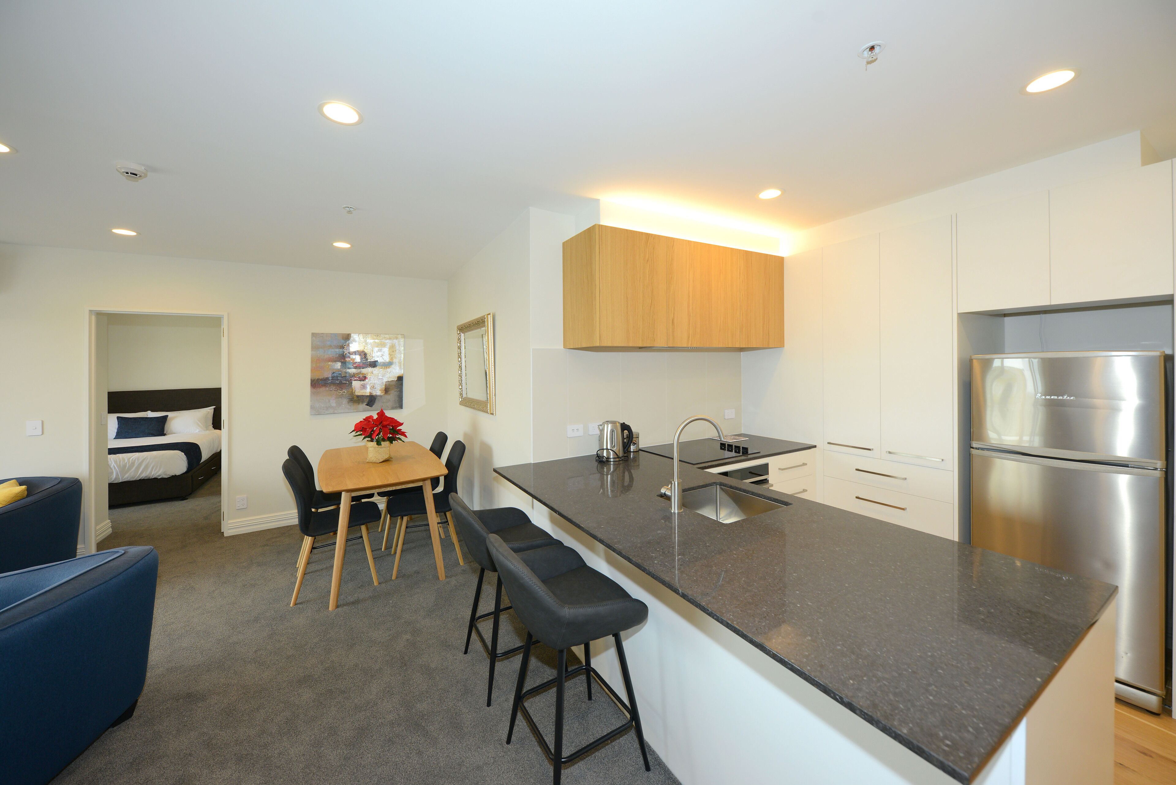 A modern kitchen with a large island, stainless steel appliances, and a dining area with a table and bar stools.