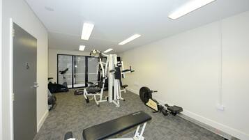 Une salle de sport équipée de matériel d’exercice, d’un banc et d’un tapis de course.