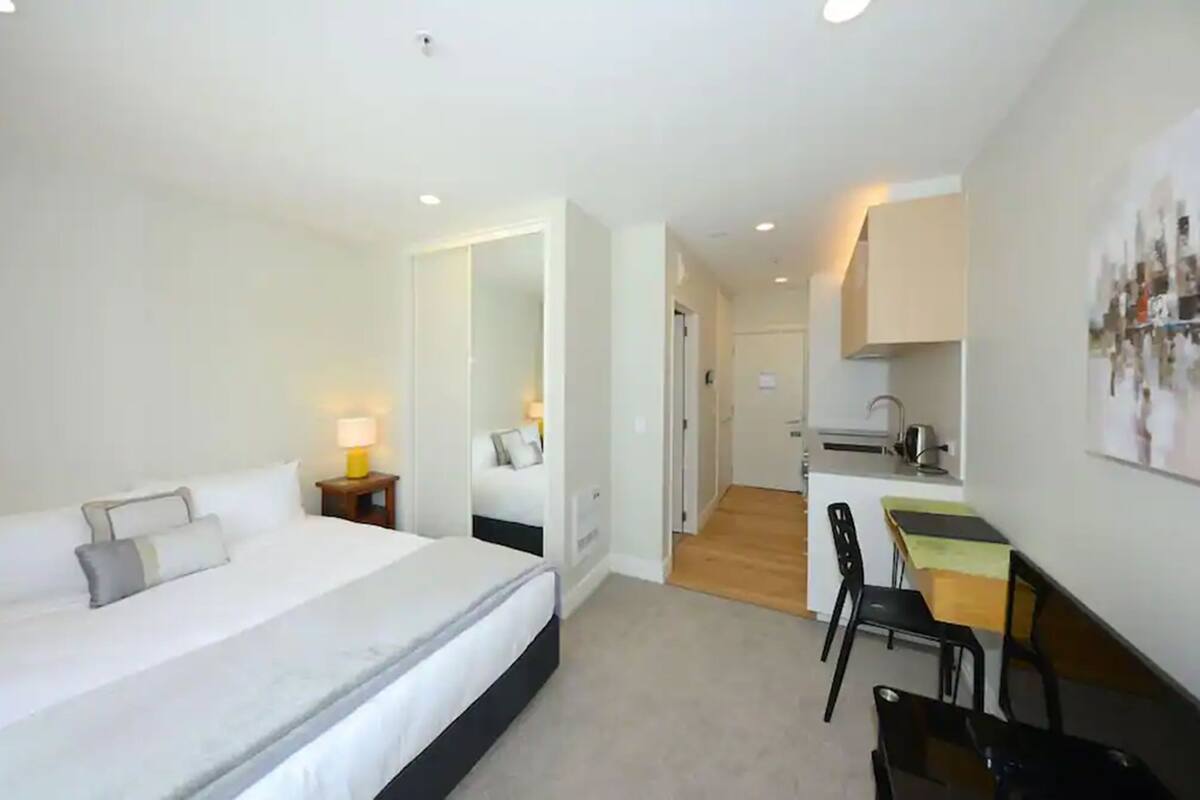 A bedroom with a bed, bedside table, and a desk area with a chair.