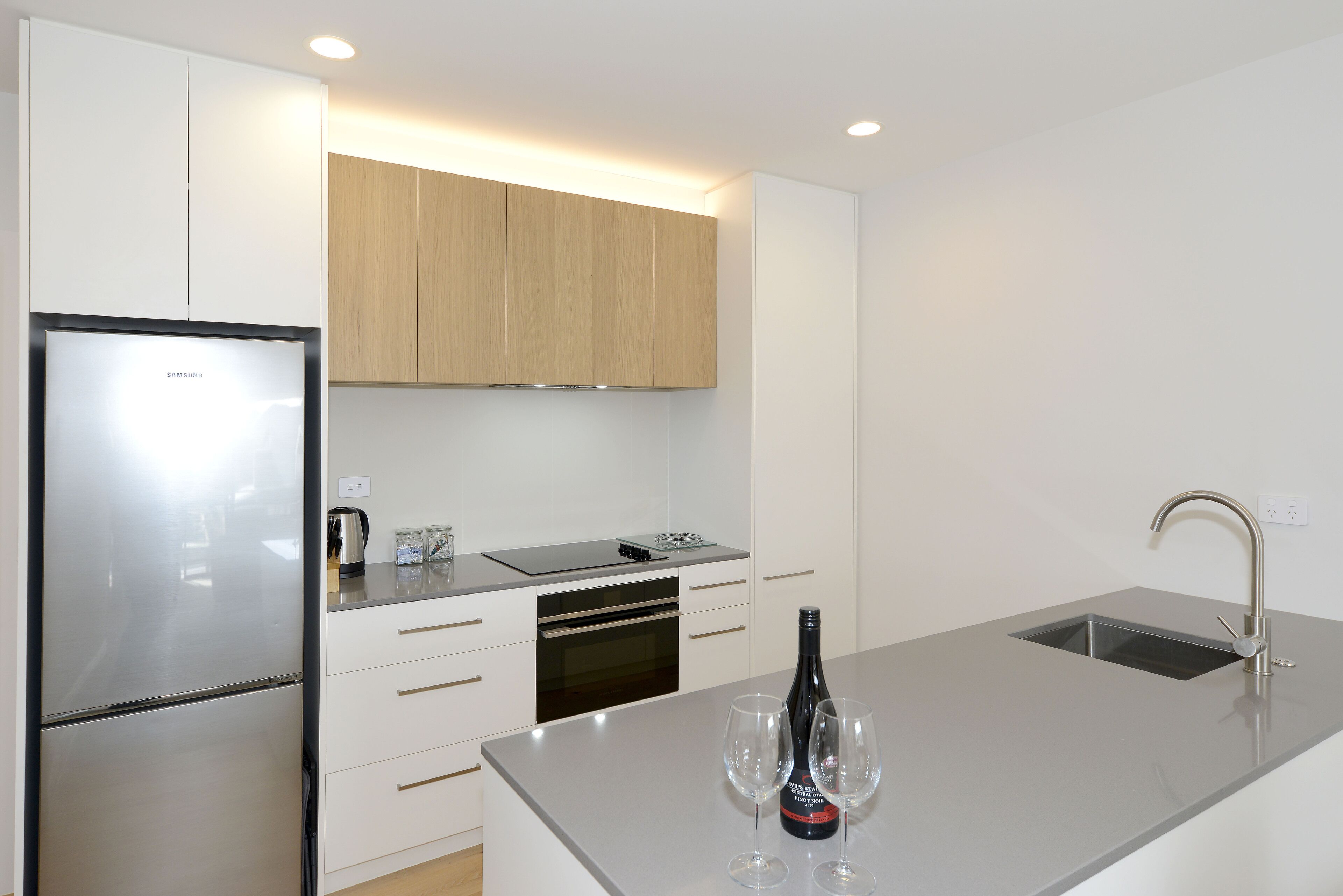 A modern kitchen with a stainless steel refrigerator, built-in oven, and a sink with a faucet.