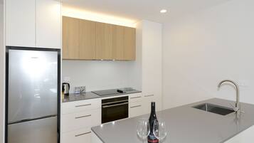 A modern kitchen with a stainless steel refrigerator, built-in oven, and a sink with a faucet.