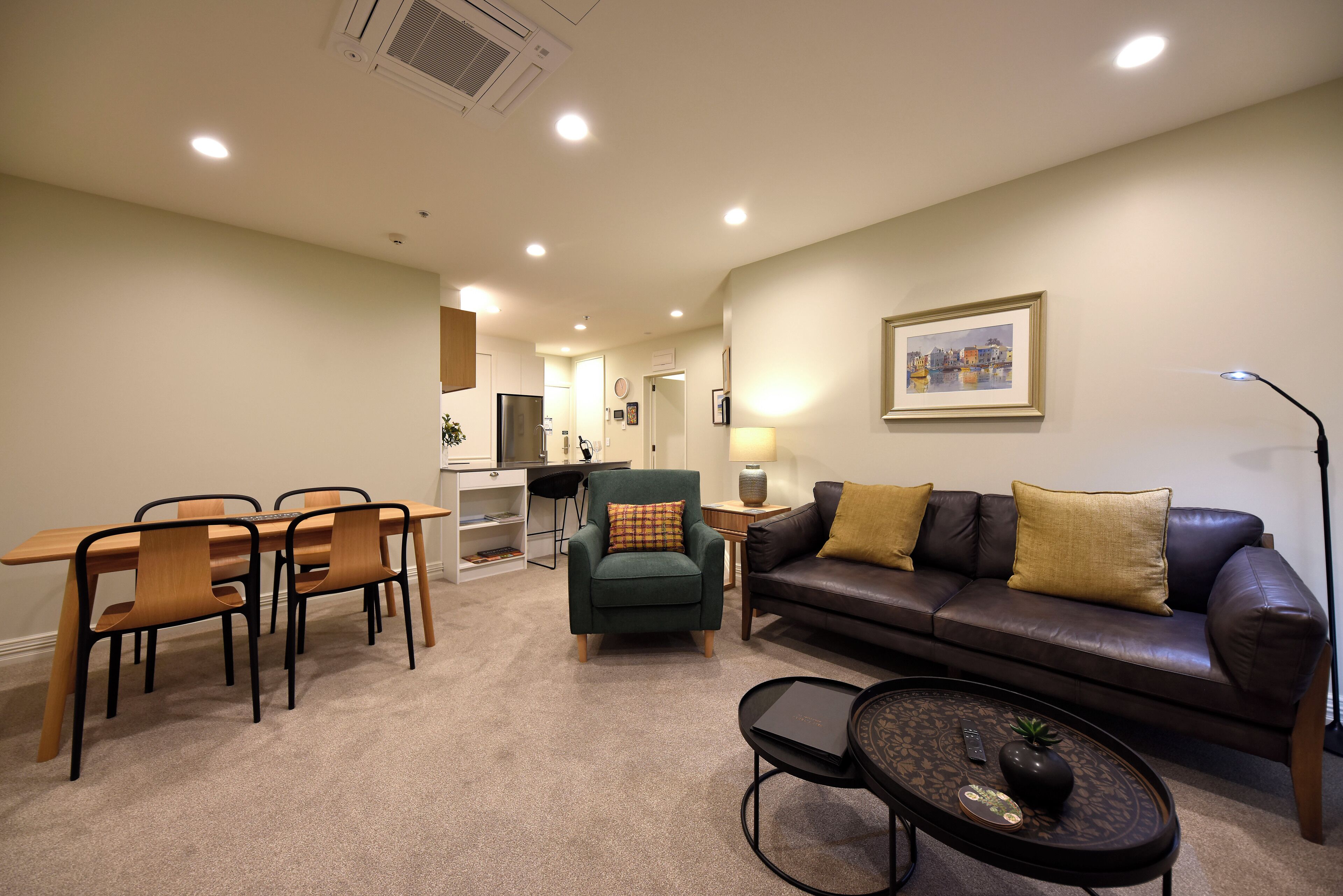 A living room with a dining area, a sofa, a coffee table, and a lamp.
