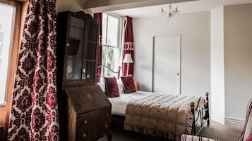 Une chambre à coucher avec un lit, une commode en bois, une chaise et une fenêtre avec des rideaux.