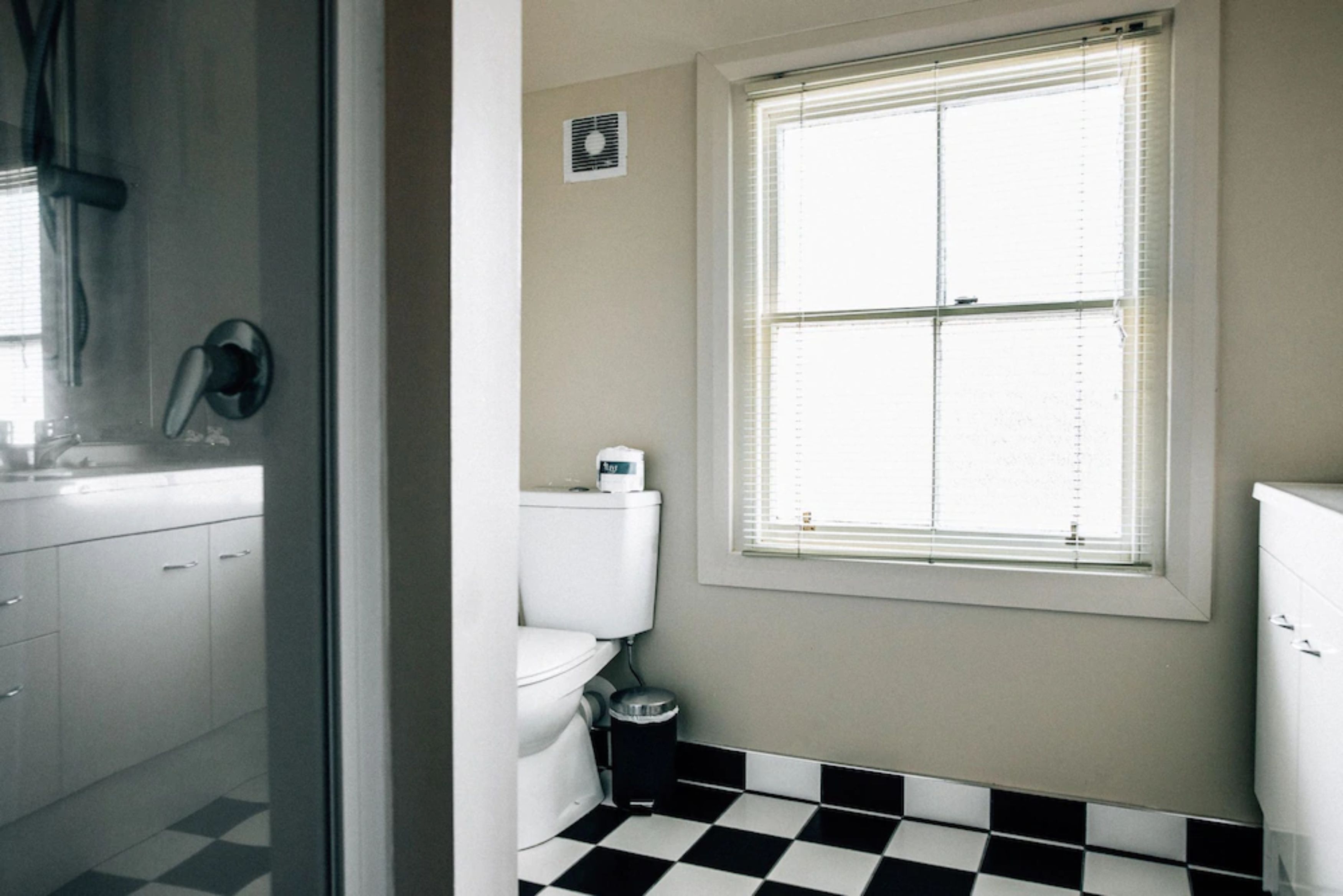 A bathroom with a toilet, sink, and window.
