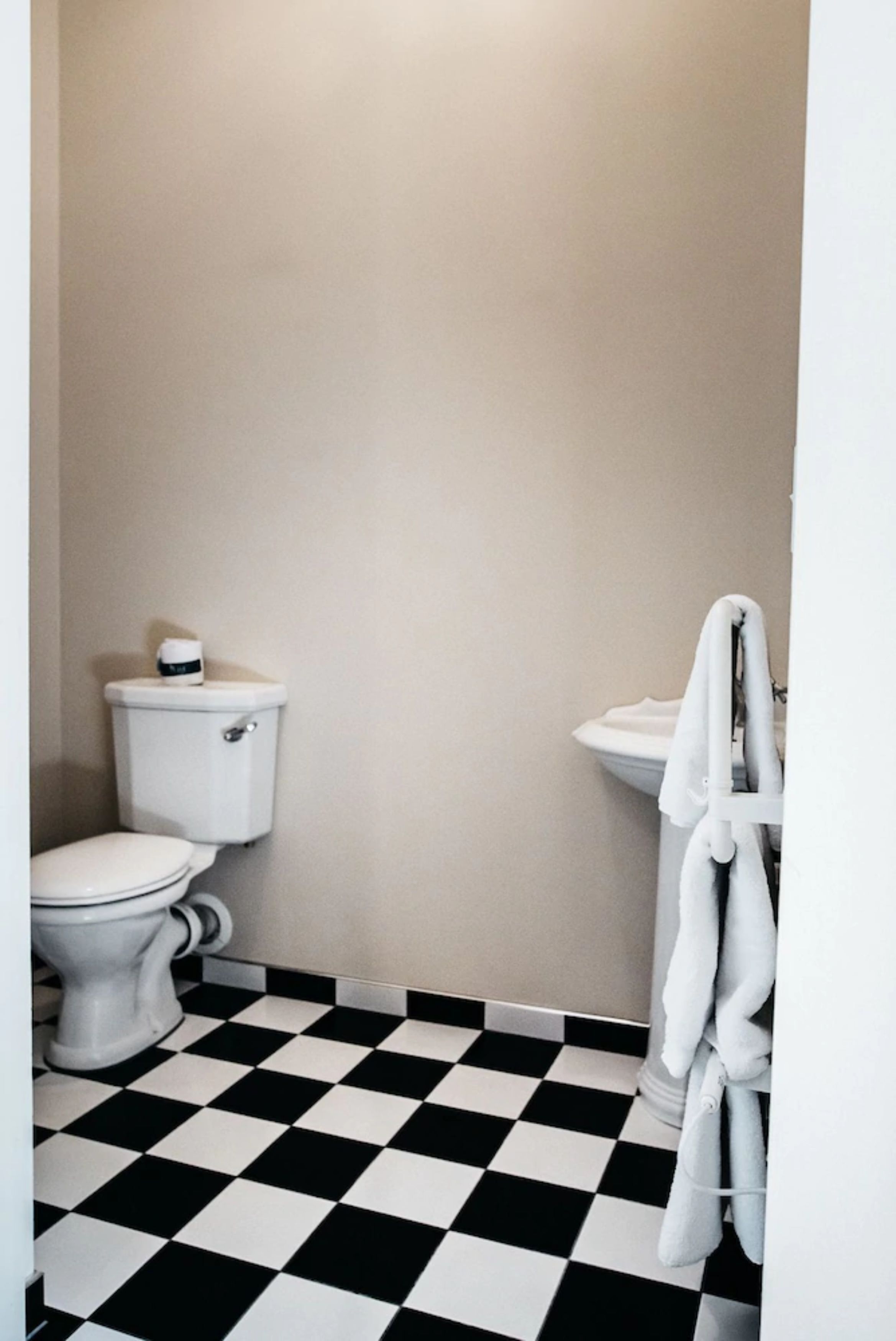 A bathroom with a toilet, sink, and checkered floor.