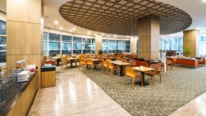 A spacious dining area with multiple tables and chairs, a buffet counter, and large windows providing natural light. - Gumi Century Hotel (Gumi)