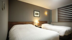 A hotel room with two beds, a nightstand with a lamp, a framed picture on the wall, and a window with blinds. - Gumi Century Hotel (Gumi)