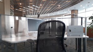 A modern office space with cubicles, a black mesh office chair, and an HP printer on a table. - Gumi Century Hotel (Gumi)