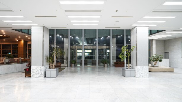 A spacious lobby with a marble floor, large glass doors leading to an elevator, and potted plants. - Gumi Century Hotel (Gumi)