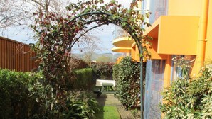 A pathway leading to a building with a yellow facade, surrounded by lush greenery and a wooden fence. - Addington Court Motel (Christchurch)