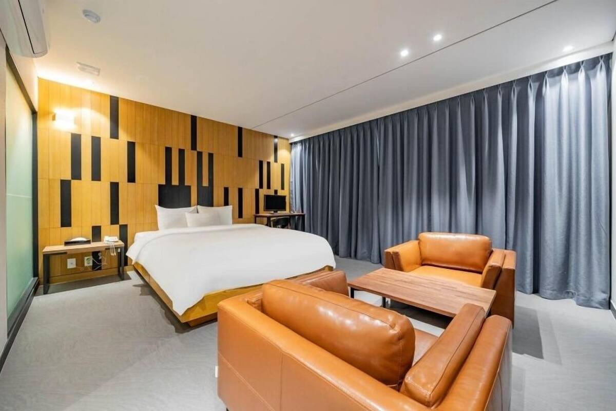 Une chambre d’hôtel moderne équipée d’un grand lit, d’un bureau, d’une chaise et d’un canapé.