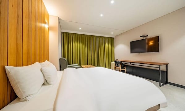 A hotel room with a large bed, a desk, a chair, a TV, and a green curtain. - F HOTEL Yeongdeungpo (Seoul)
