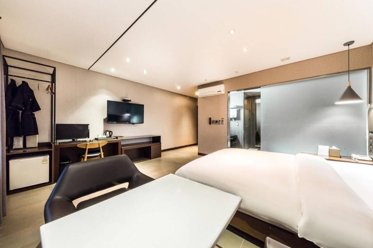 Une chambre d’hôtel moderne équipée d’un lit, d’un bureau, d’une télévision et d’une armoire.