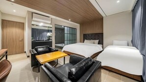 Una habitación de hotel con cama, sofá, una mesita, escritorio y espejo.