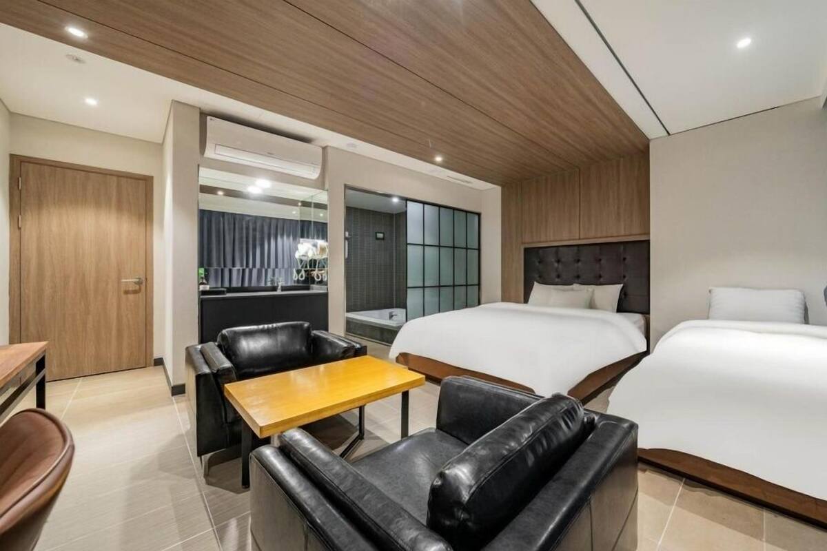 Une chambre d’hôtel avec un lit, un canapé, une petite table, un bureau et un miroir.