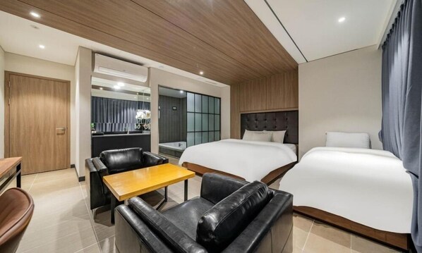 Una habitación de hotel con cama, sofá, una mesita, escritorio y espejo.