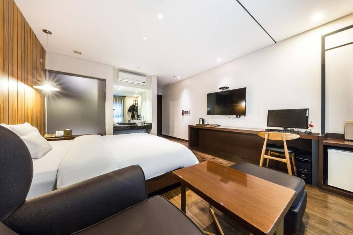 Une chambre d’hôtel comprenant un lit, un bureau avec une chaise, une télévision et une kitchenette.