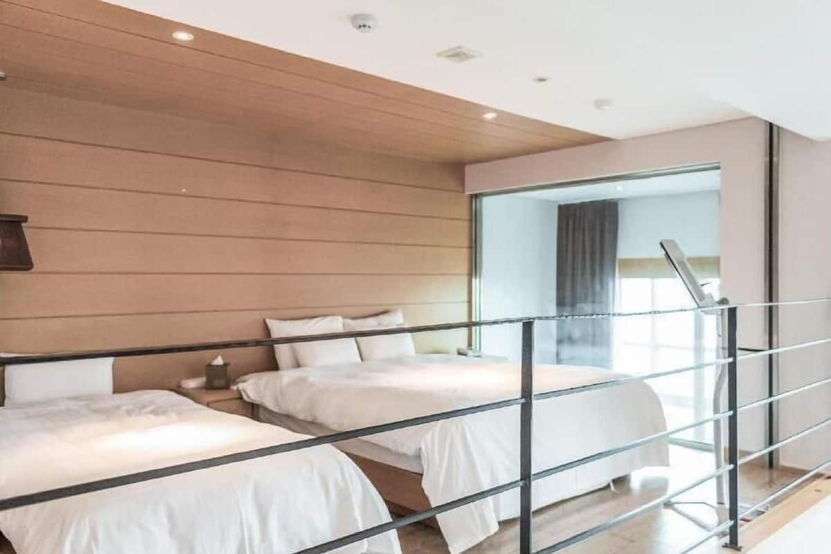 Une chambre d’hôtel moderne avec deux lits, un mur en bois, une cloison en verre et une vue sur la ville.