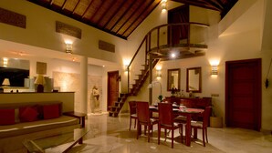 A spacious living area with a dining table, chairs, a sofa, and a staircase leading to an upper level. - Mayana Villas (Canggu)
