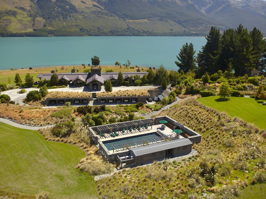 Ein Resort mit Schwimmbad, einem großen Gebäude und einem See im Hintergrund.