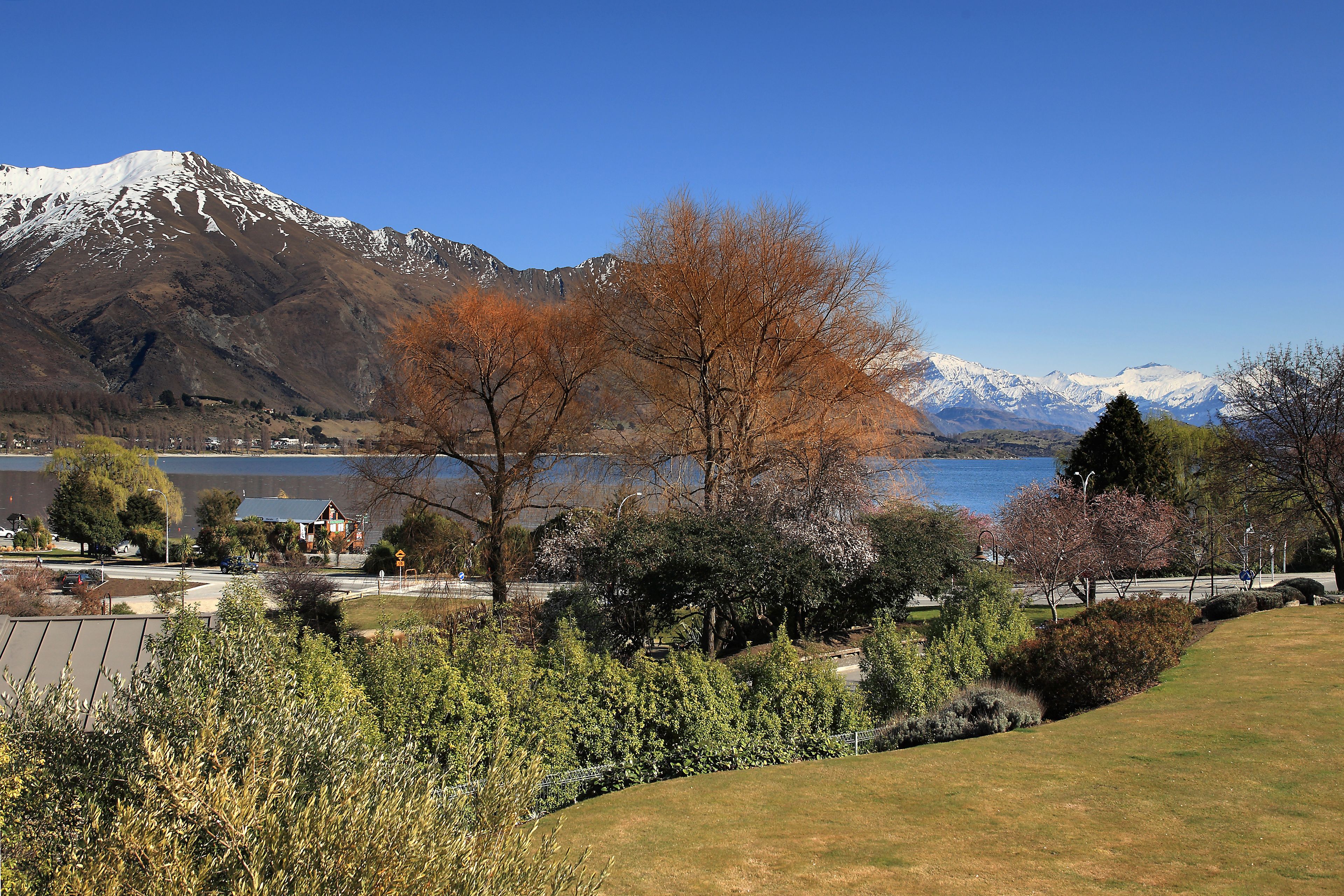 A mountainous landscape with a lake, trees, and a building in the foreground.