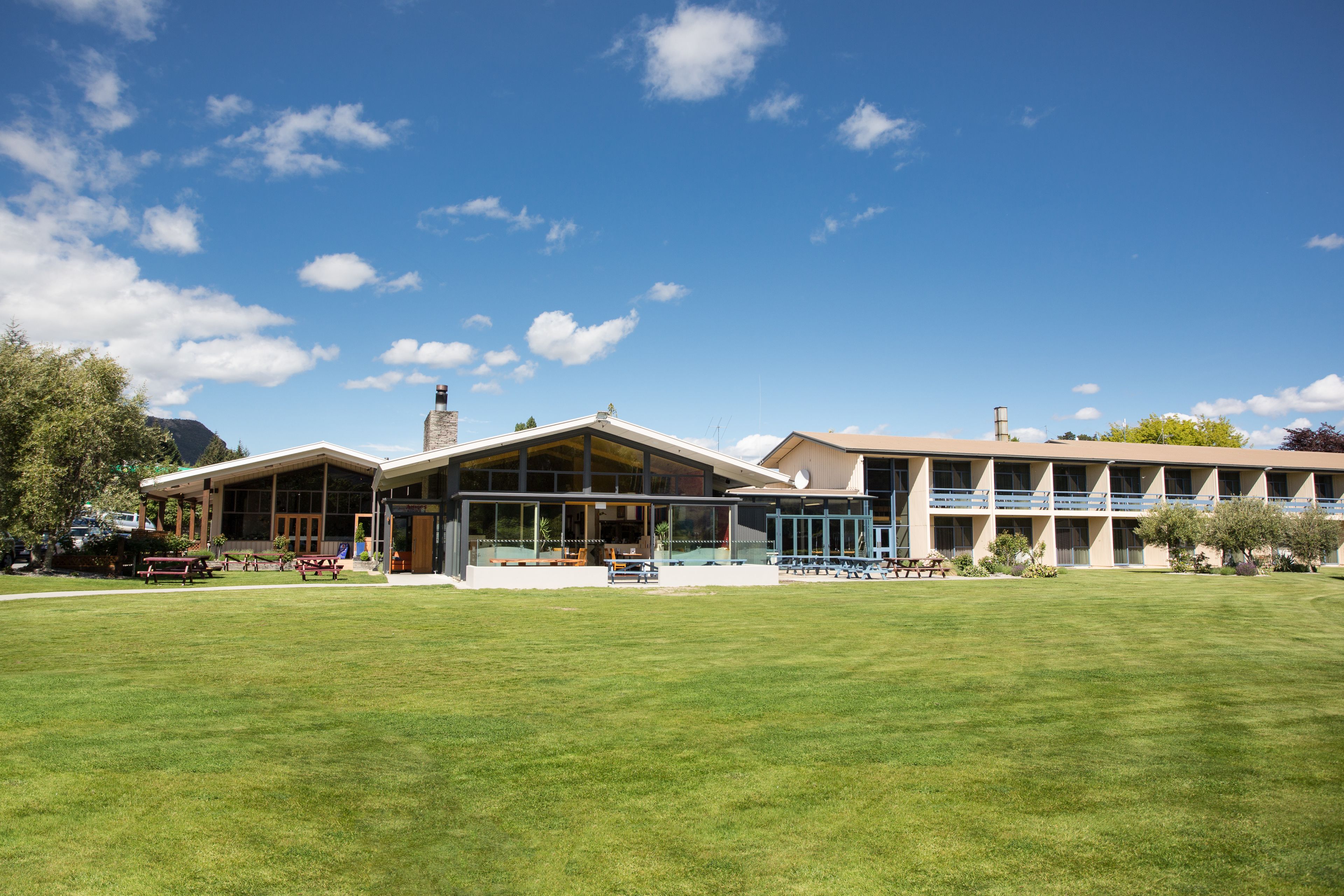 A modern building with a large lawn in front, featuring a mix of glass and brick architecture.