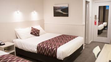 A hotel room with a bed, bedside table, and a painting on the wall.