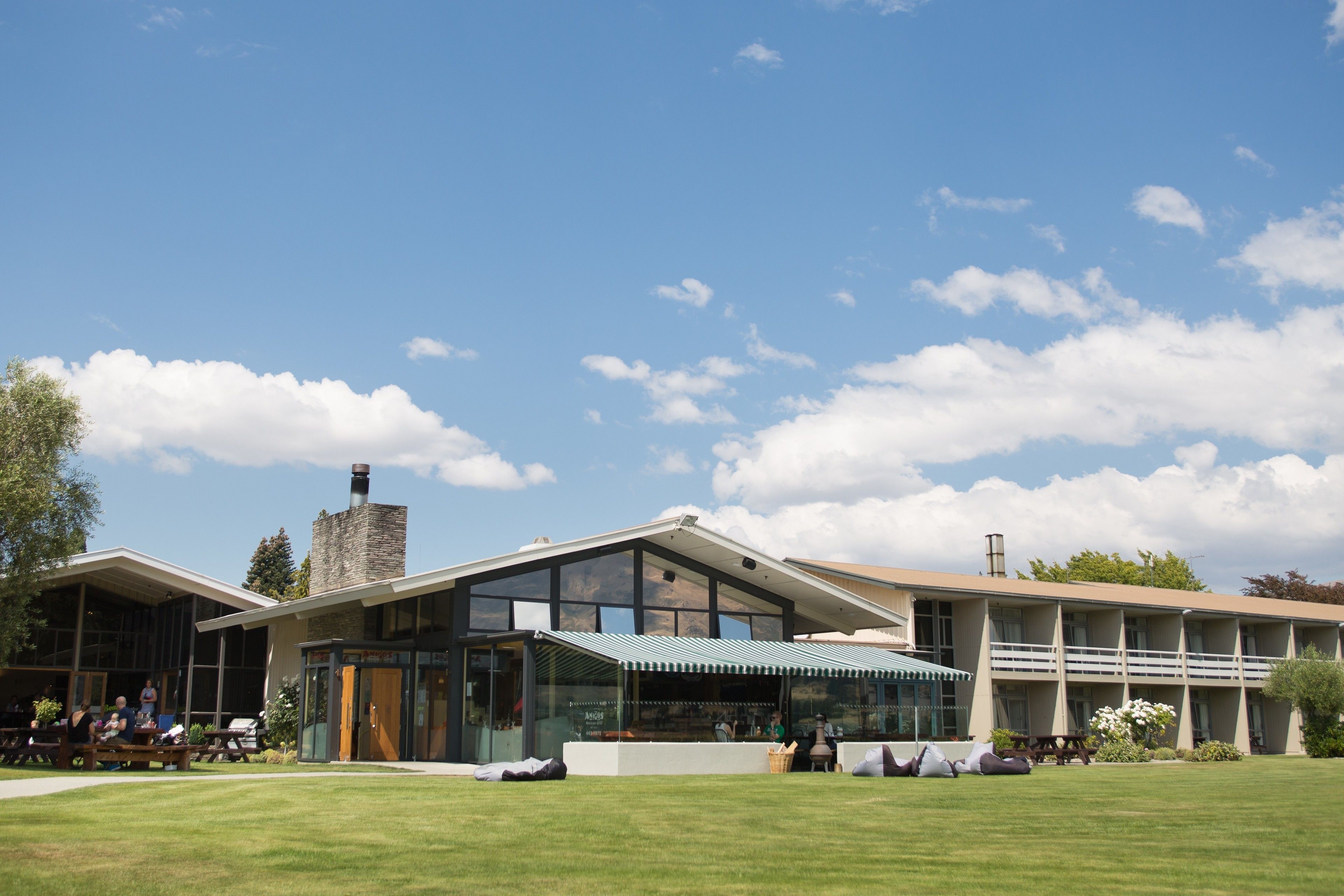 Un bâtiment moderne doté de grandes fenêtres, d’un patio couvert et d’une pelouse verdoyante.