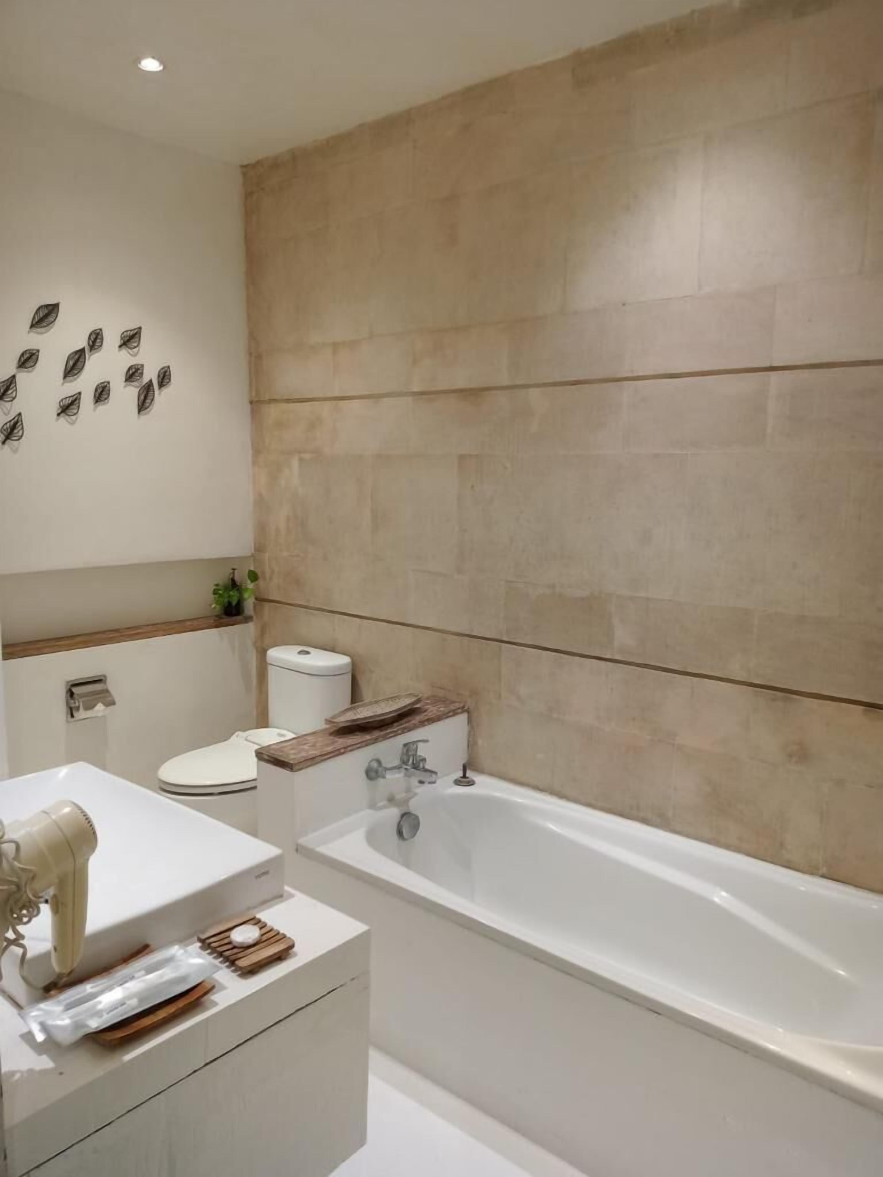 Ein modernes Badezimmer mit einem weißen Waschbecken, einer Toilette und einer Badewanne.