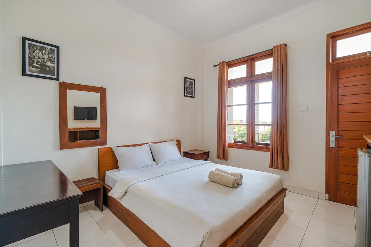 A neatly arranged bedroom with a bed, bedside table, and a TV mounted on the wall.