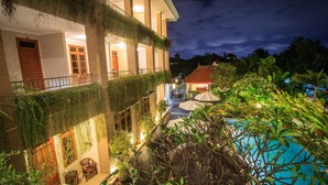 Un hotel con piscina, mobiliario exterior y abundante vegetación.